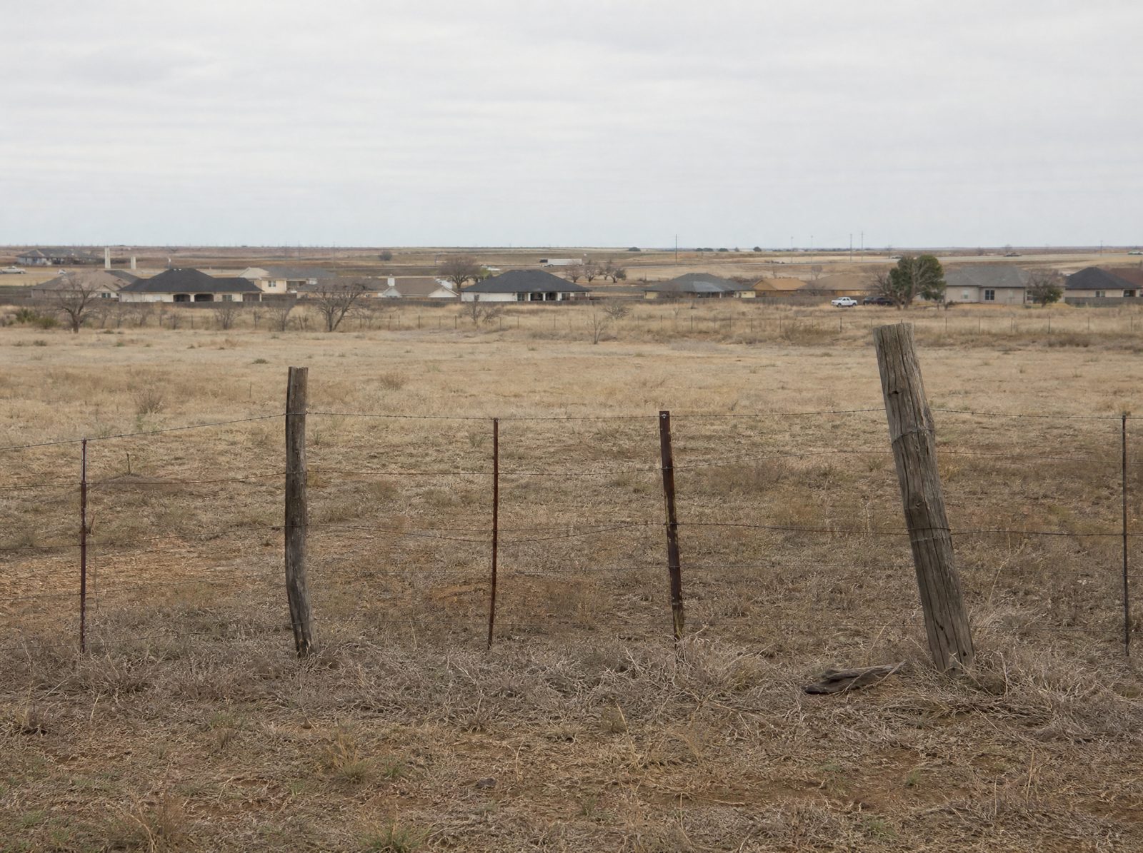 Rural and residential property near the SH 99 corridor in Fort Bend County, a wire fence line and open land stretching toward a distant highway