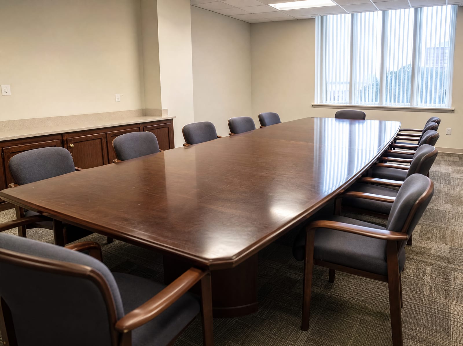 An empty plain government hearing room with a long wooden table and chairs and neutral walls where special commissioners assess damages, under even daylight
