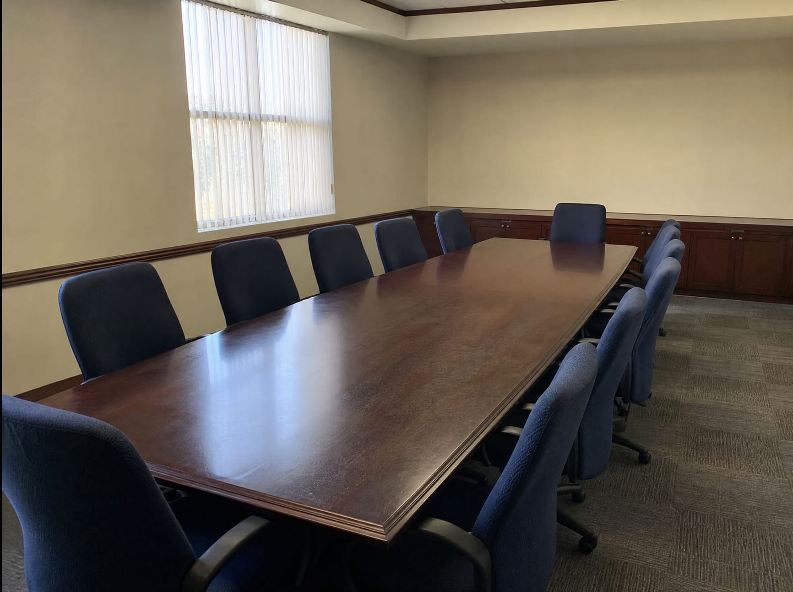 An empty plain government hearing room with a long wooden table and chairs and neutral walls where special commissioners assess damages, under even daylight