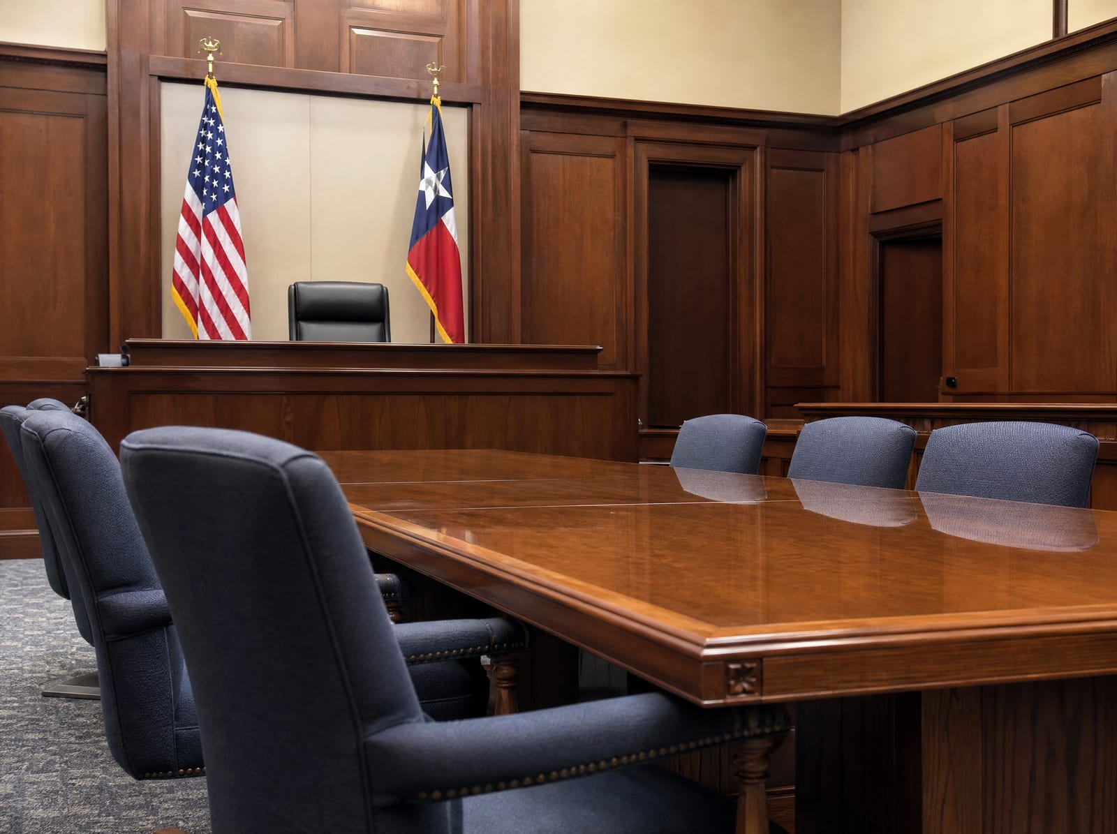 An orderly courthouse hearing room with a long polished wood table, upholstered chairs, a United States flag and a Texas flag, and wood-paneled walls, where a breach-of-fiduciary-duty claim is litigated