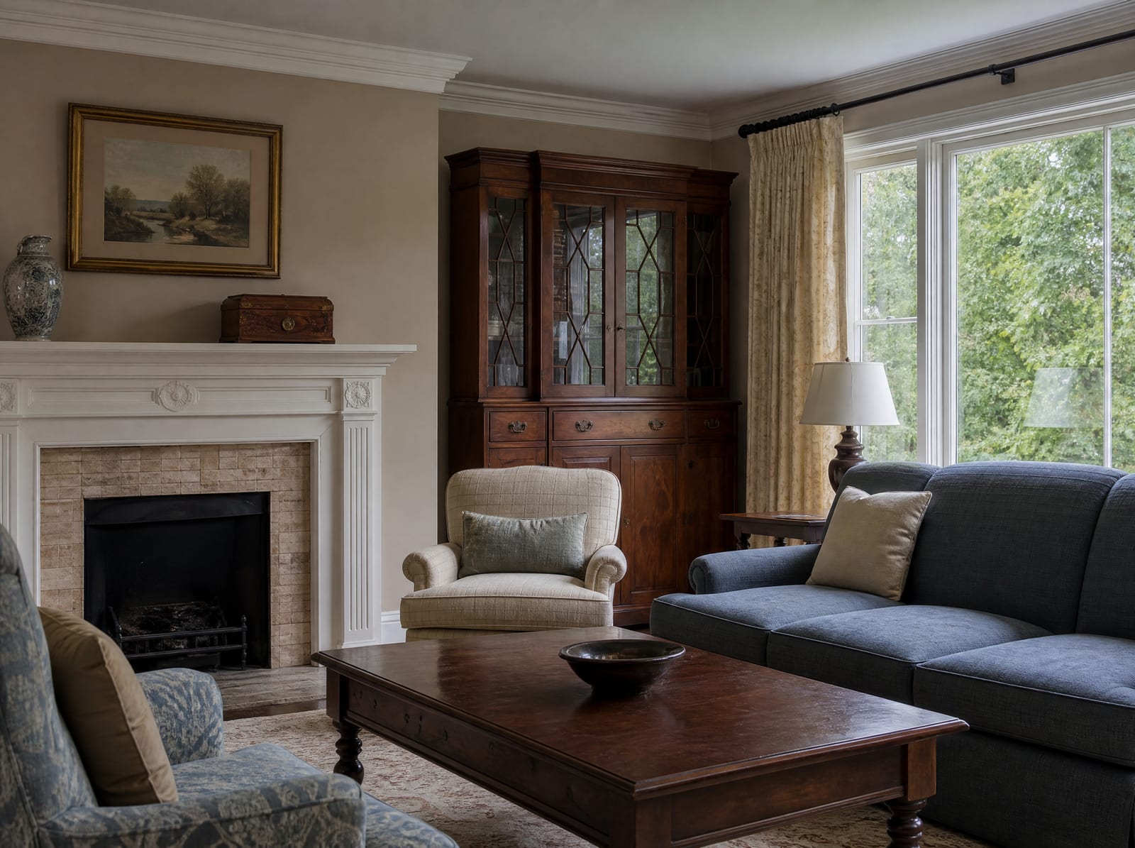A quiet, traditional family living room with a sofa, armchairs, and a fireplace mantel holding a keepsake box and a vase, the emotional stakes of a contested estate