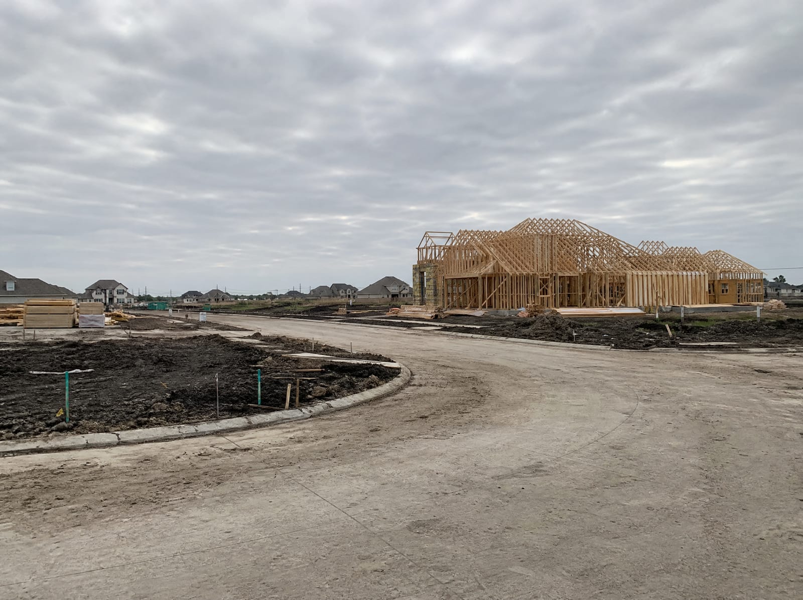 A newer suburban subdivision under development near Katy, Texas, with freshly graded lots, new concrete curbs and streets, and homes under construction transitioning into master-planned suburbia