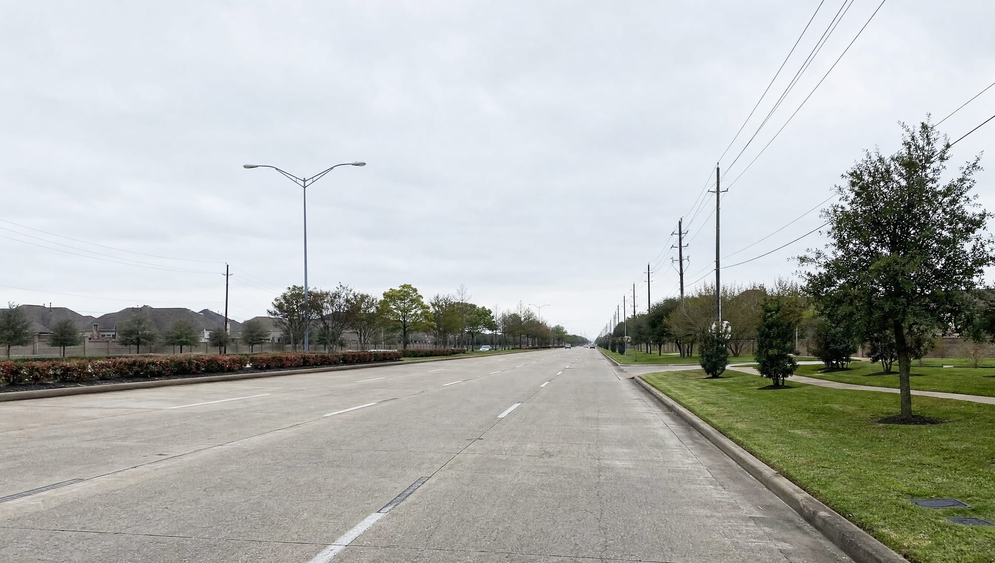 The State Highway 6 corridor running through Missouri City, Texas in Fort Bend County, a wide multi-lane suburban arterial with landscaped medians, utility lines, low commercial frontage, and established suburban development under a big pale sky