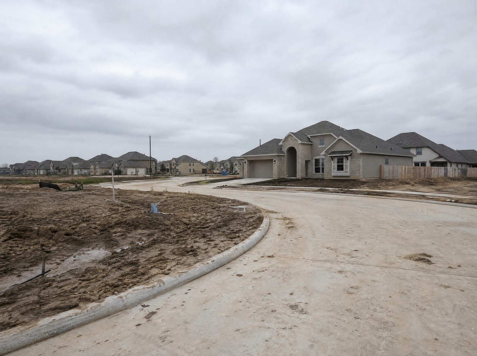 A newer subdivision under development in the Sienna area near Missouri City, Texas, with freshly graded lots, new concrete curbs and streets, and open cleared Fort Bend land transitioning into master-planned suburbia